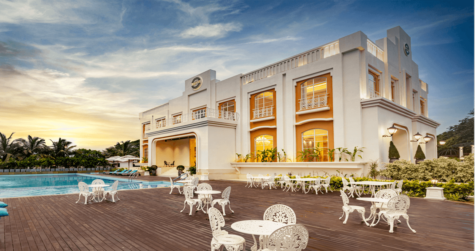 The Imperial Goa clubhouse with a pool and timber deck at sunset